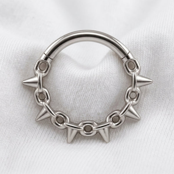 Anneau clicker argente 5 spikes chaine — pose sur tissu blanc