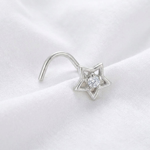 Clou nez argente etoile ajouree — pose sur tissu blanc