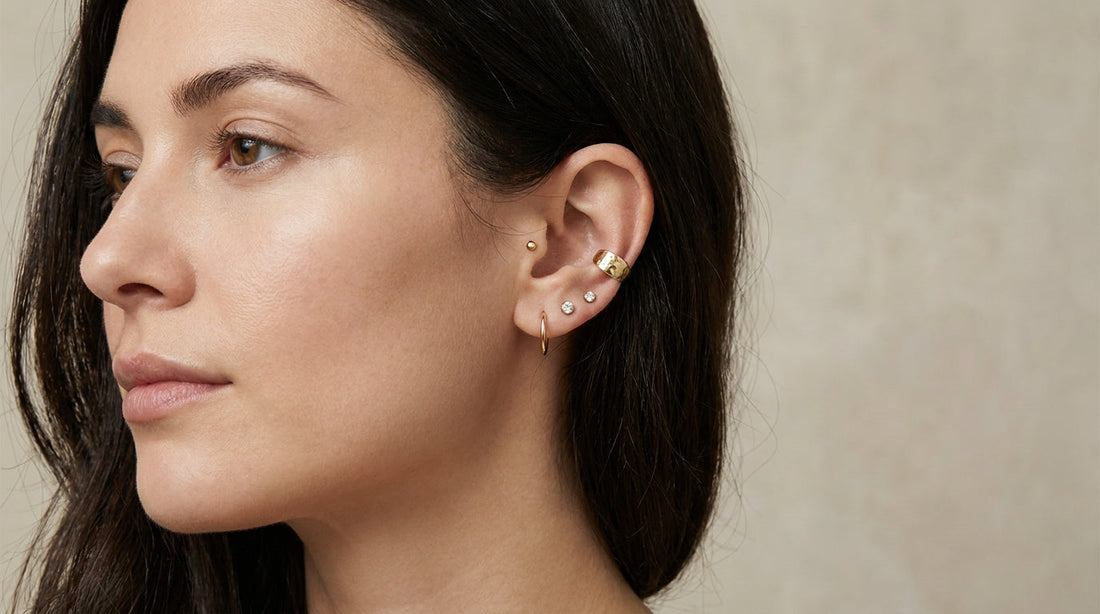 Femme de profil portant un ear stack doré composé de puces de lobe, d'un hélix et d'un conch