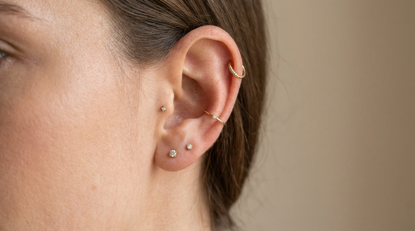Oreille feminine elegante portant plusieurs piercings dores : helix, tragus, conch et lobe