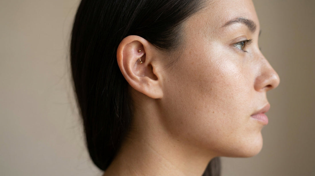 Femme de profil portant un piercing rook doré sur le pli de cartilage interne de l'oreille