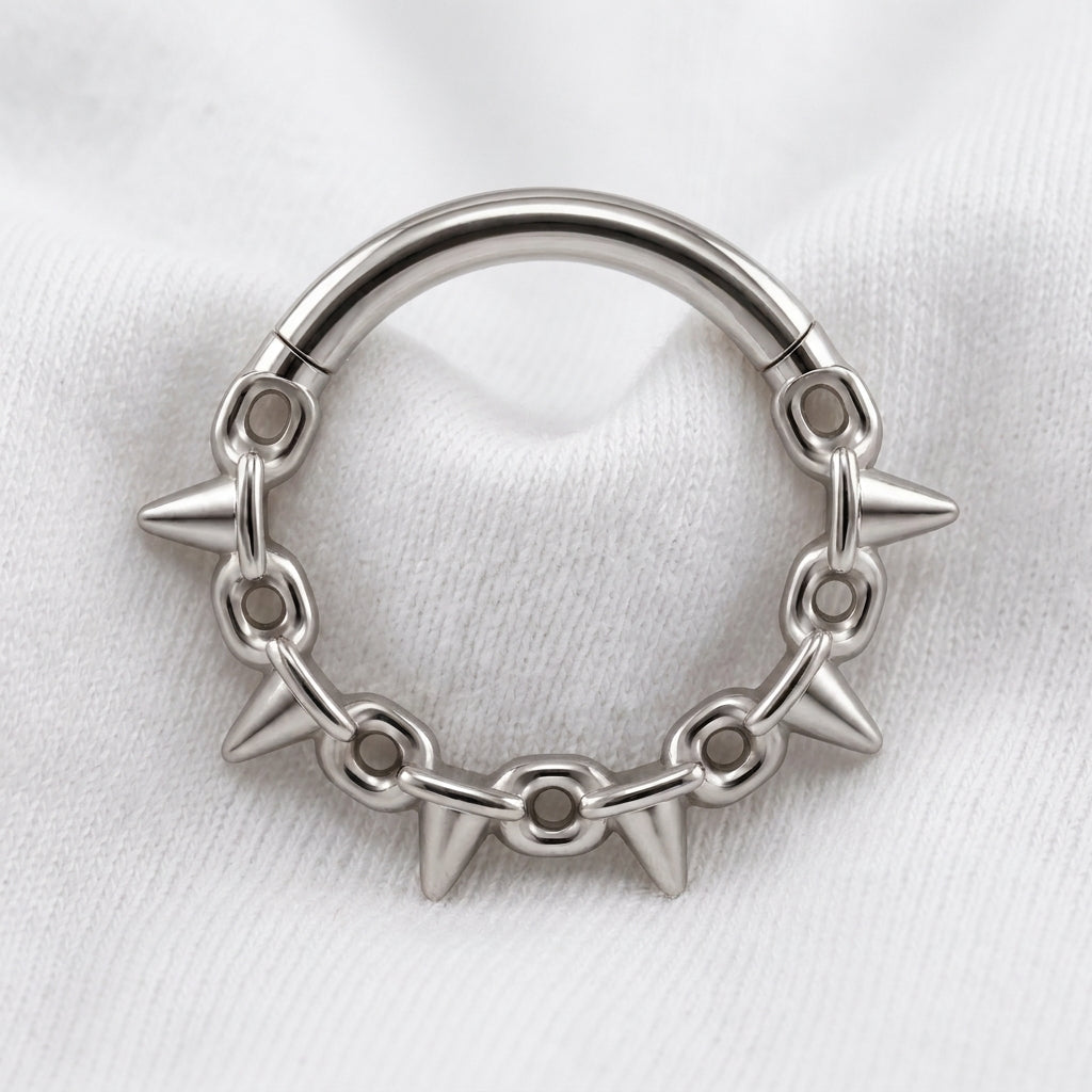Anneau clicker argente 5 spikes chaine — pose sur tissu blanc