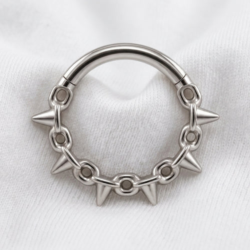 Anneau clicker argente 5 spikes chaine — pose sur tissu blanc