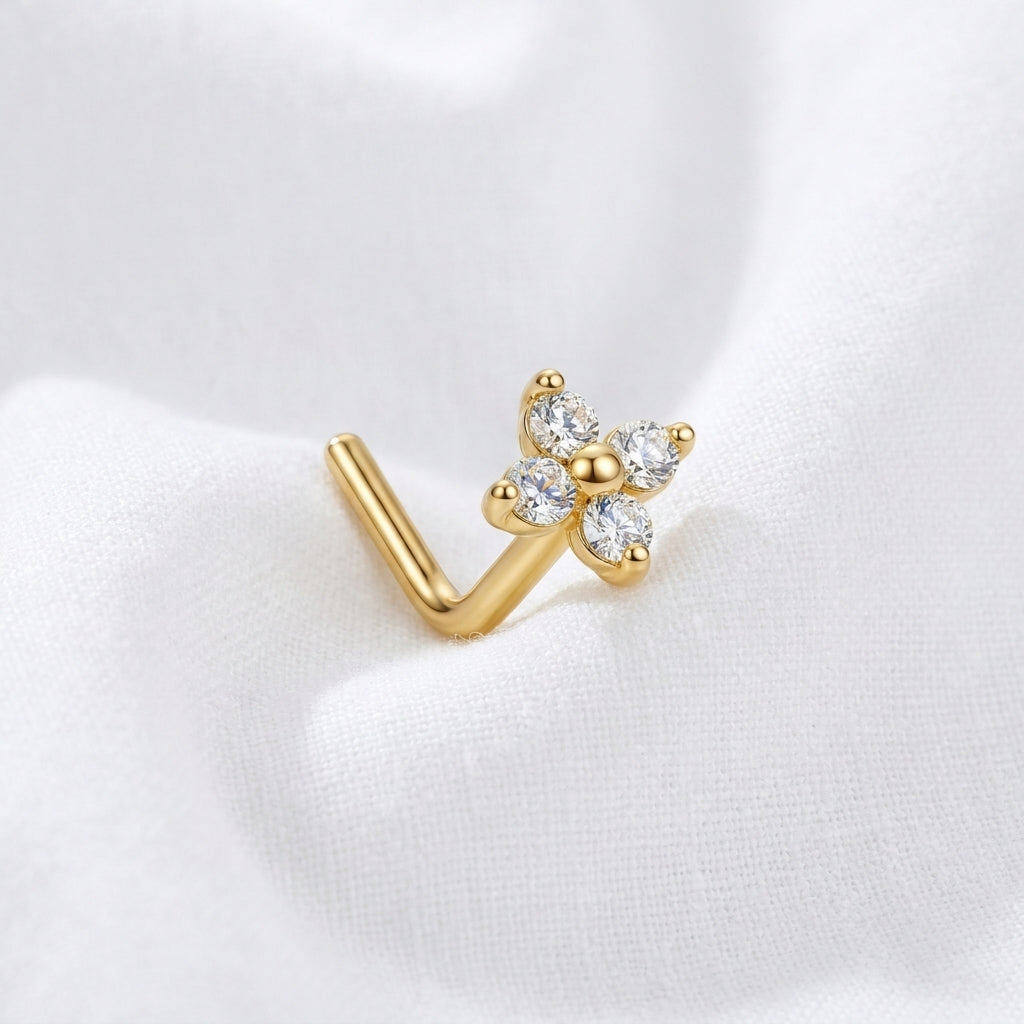 Clou en L dore fleur 4 petales zircons — pose sur tissu blanc