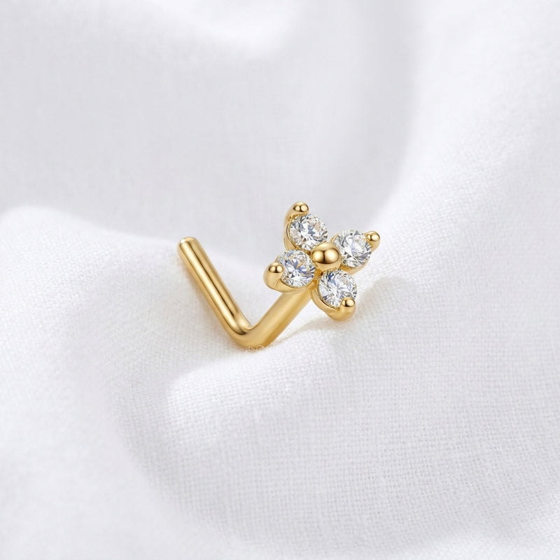 Clou en L dore fleur 4 petales zircons — pose sur tissu blanc