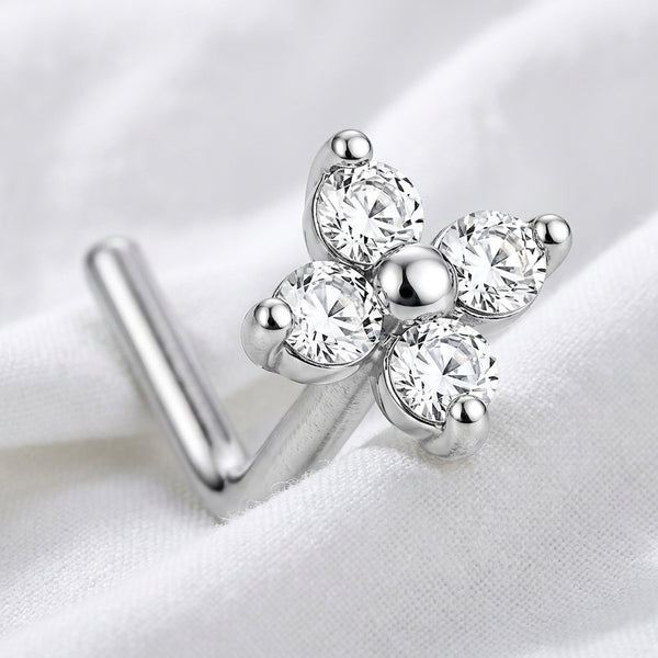 Clou en L argente fleur 4 petales zircons macro — pose sur tissu blanc