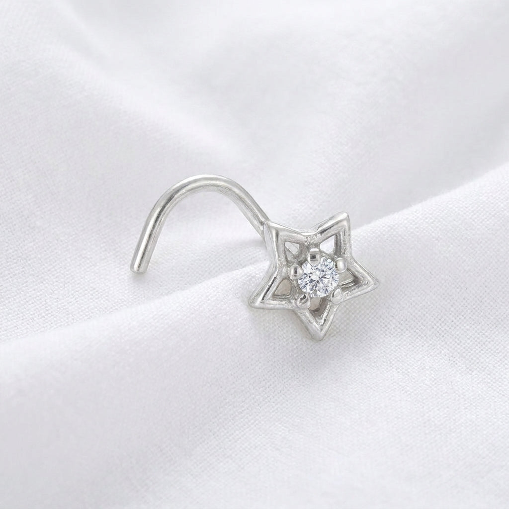 Clou nez argente etoile ajouree — pose sur tissu blanc