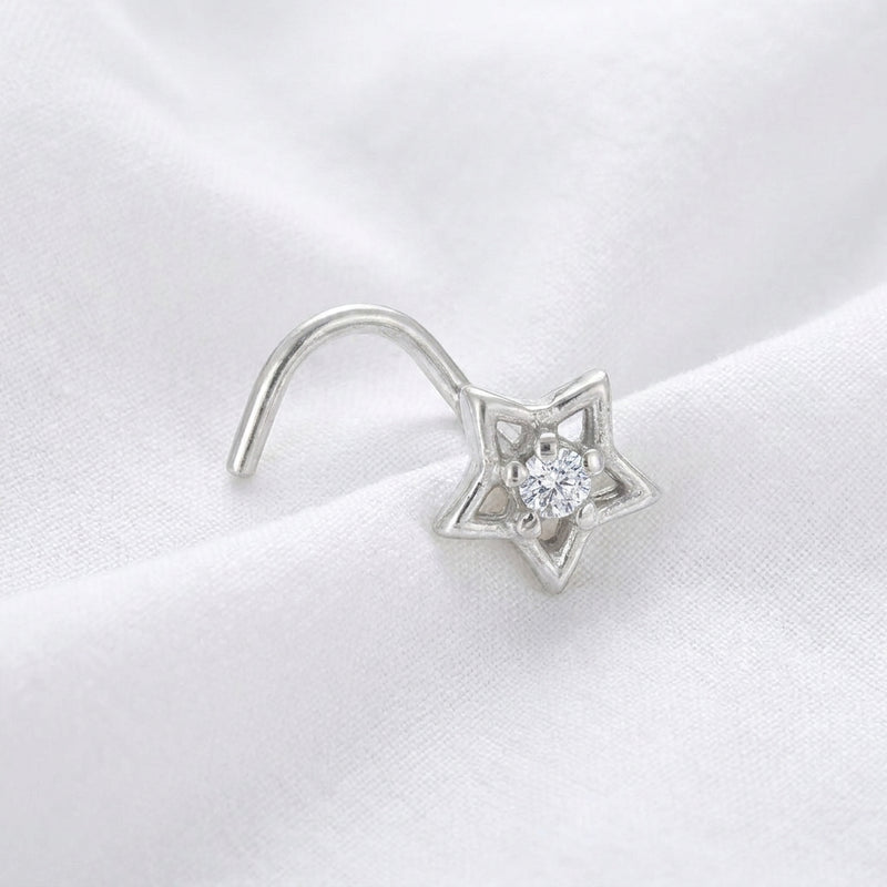 Clou nez argente etoile ajouree — pose sur tissu blanc
