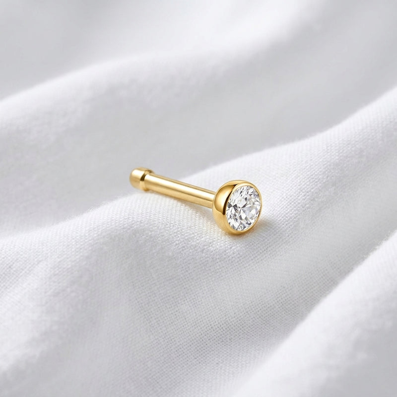 Tige droite nez doree zircon bezel — posee sur tissu blanc