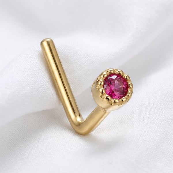 Clou en L dore zircon rouge rubis bezel milgrain — pose tissu blanc