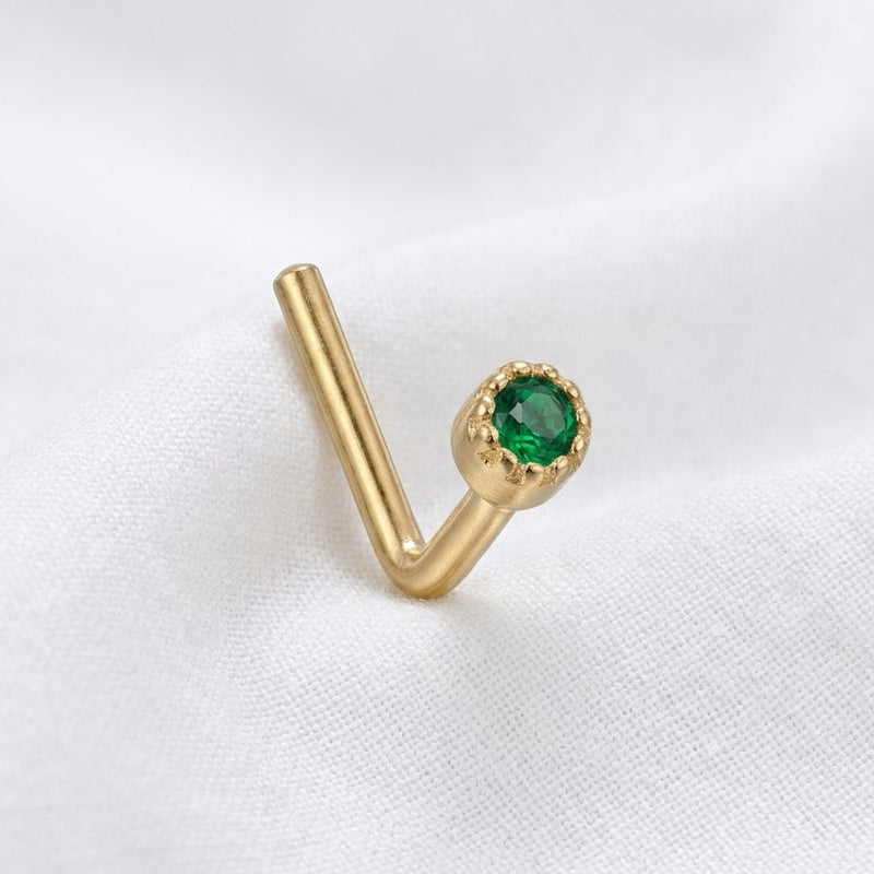 Clou en L dore zircon vert emeraude bezel milgrain — pose tissu blanc