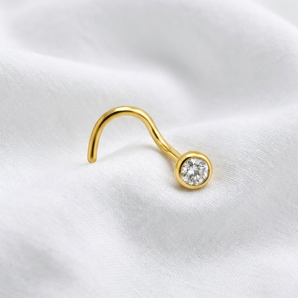 Vis nez doree zircon rond sertissage bezel — macro tissu blanc pierre avant-plan