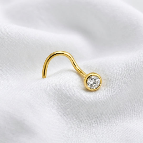 Vis nez doree zircon rond sertissage bezel — macro tissu blanc pierre avant-plan