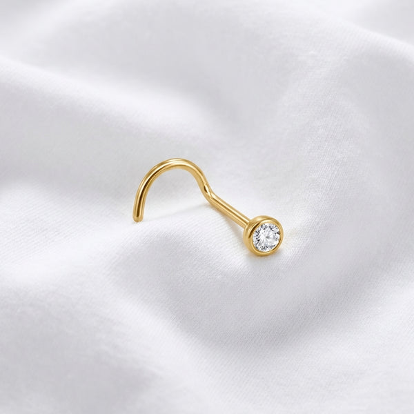 Vis nez doree zircon rond sertissage bezel — macro pose tissu blanc inclinee