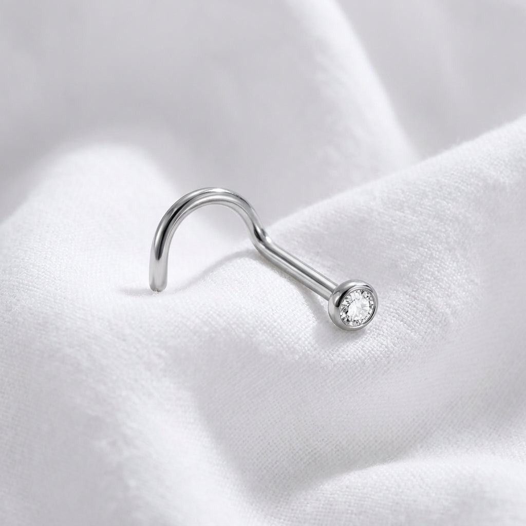 Vis nez argentee zircon rond sertissage bezel — macro pose tissu blanc