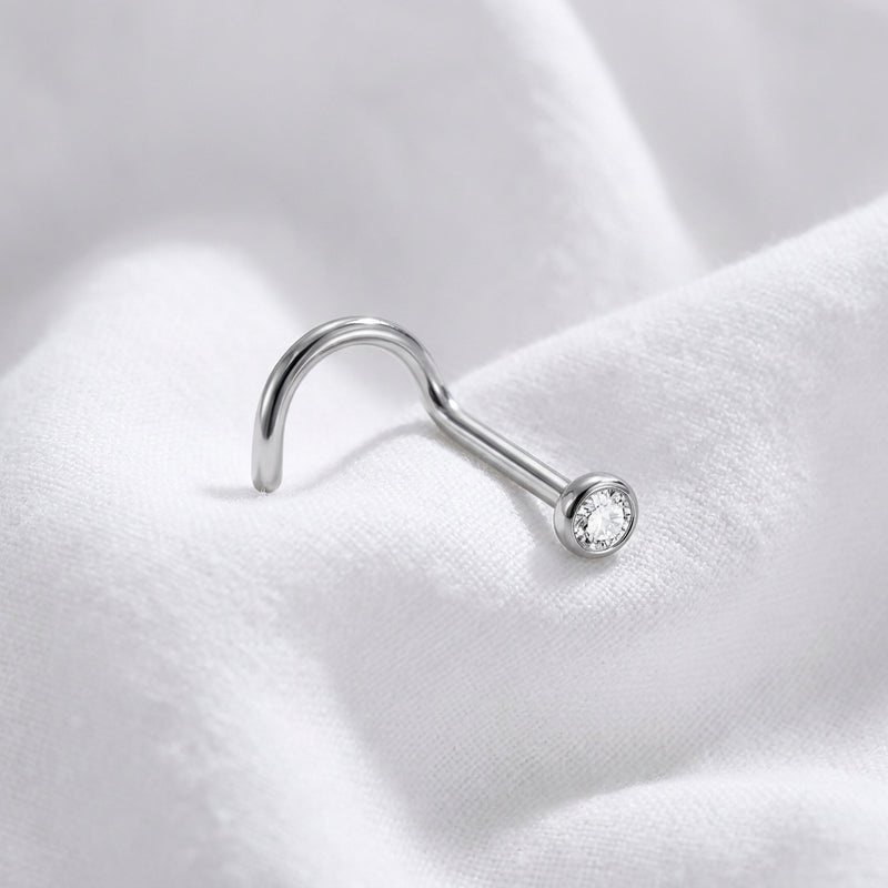 Vis nez argentee zircon rond sertissage bezel — macro pose tissu blanc